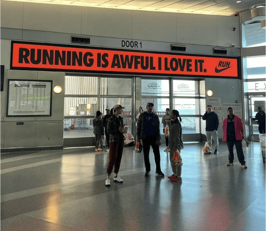 Photo of runners underneath a Nike sign saying "running is awful i love it"