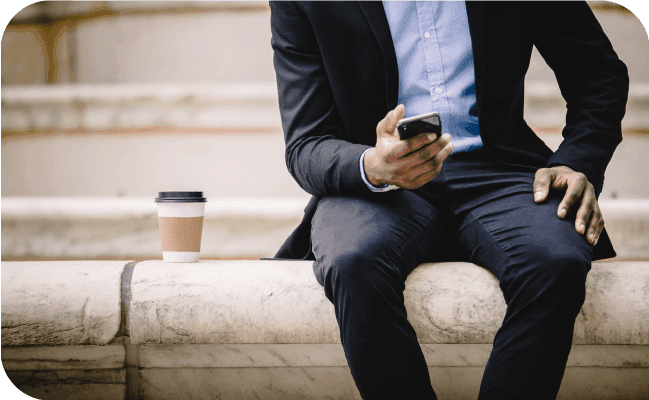 Businessman sitting on steps with his smartphone