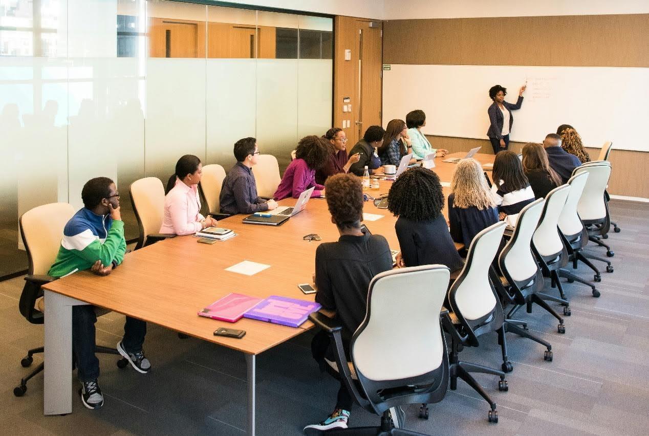 Business meeting around a conference table with presenter at the whiteboard