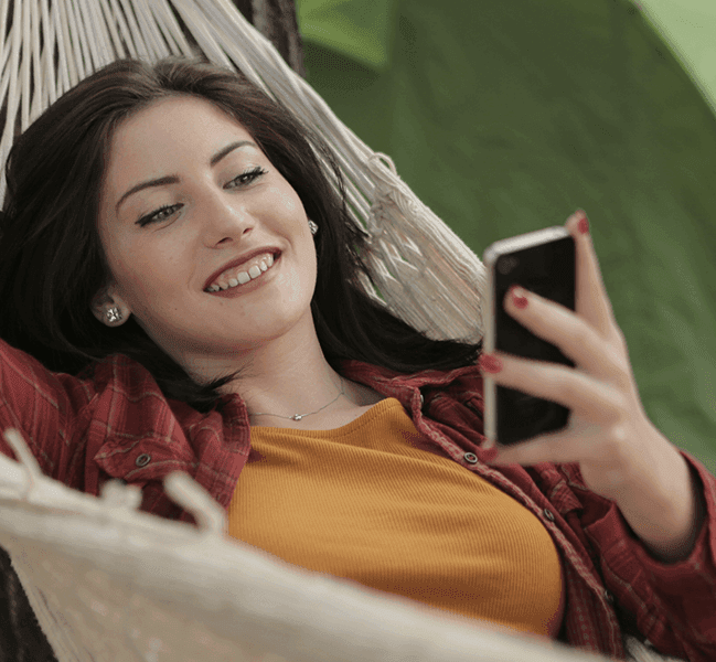 Happy woman texting in hammock