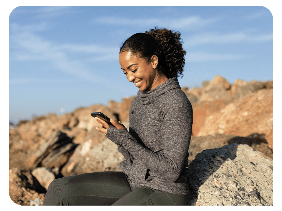 Woman sending a text while sitting on a rock