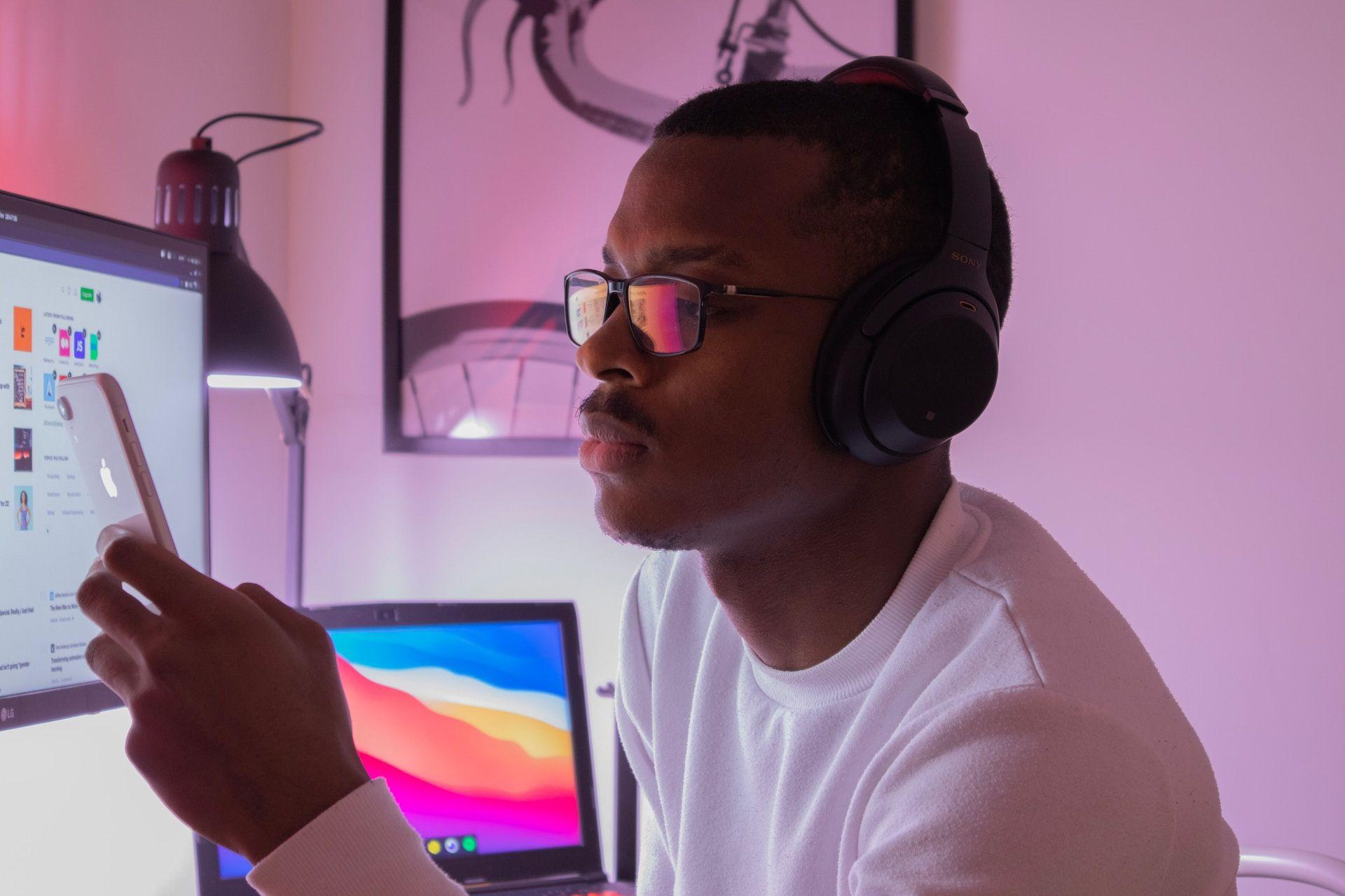 Man with headphones on phone with colorful monitor in background