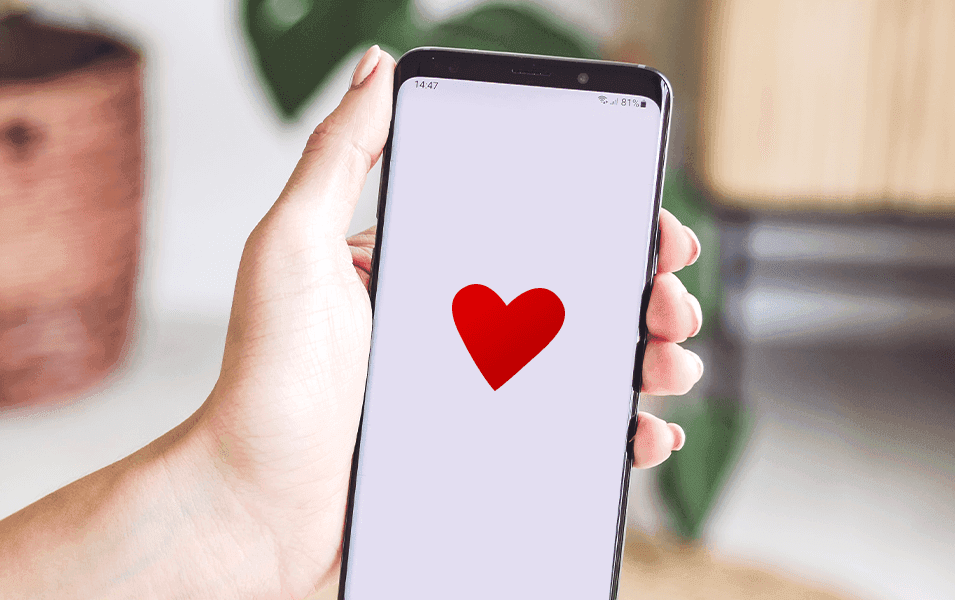 Hands holding a smartphone with a heart symbol on the screen